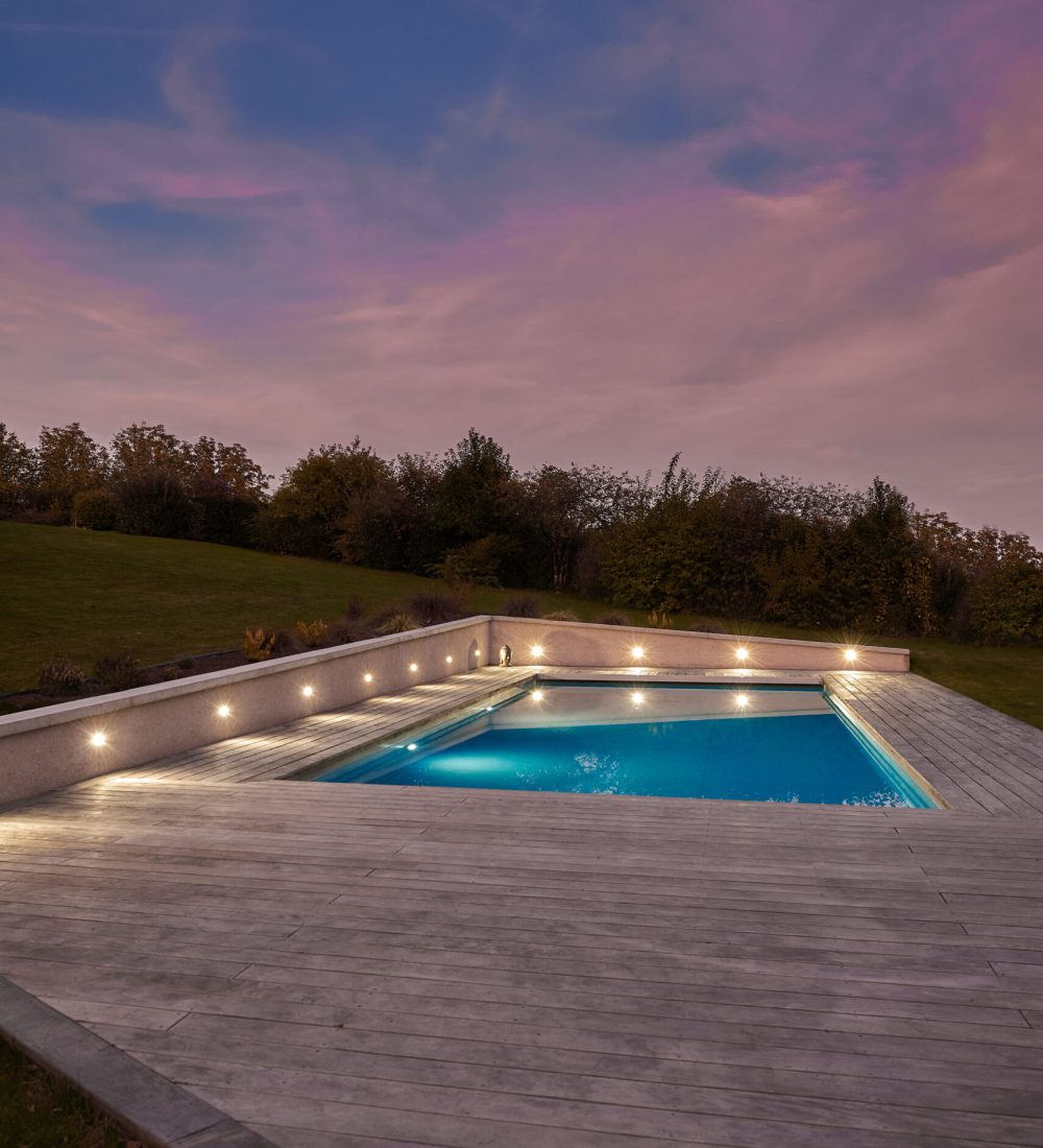 Piscine extérieure de 11 x 4.5 m avec spot leds et plage en bois exotique